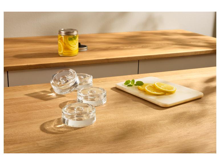 Photophores en verre sur un comptoir en bois avec citrons et menthe.