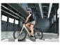 Femme avec casque et lunettes de soleil à vélo électrique dans un hall intérieur.