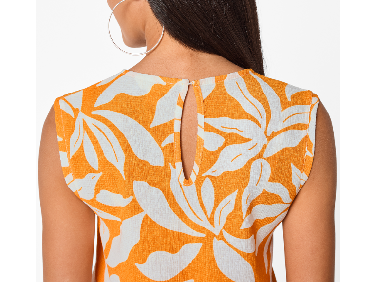 Dos d'une femme portant un haut orange à motifs floraux blancs avec une découpe.