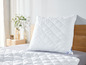 Une couette blanche avec un oreiller sur un lit.