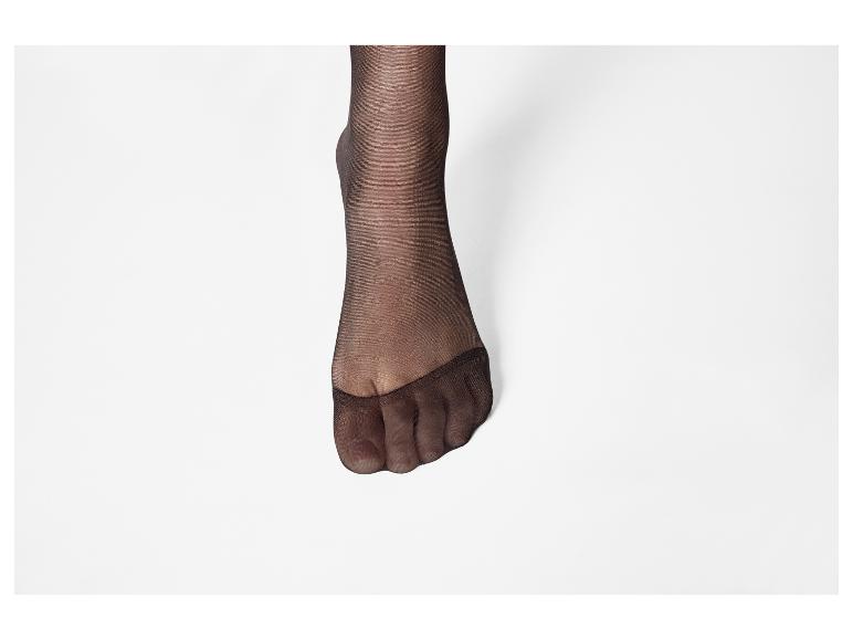Pied de femme avec des collants noirs sur fond blanc.