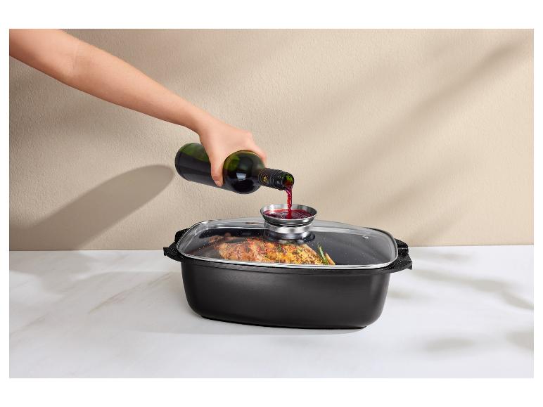 Main versant du vin rouge dans une cocotte avec couvercle en verre, contenant des aliments cuits.