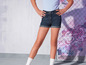 Une femme porte un short en jean et des chaussettes blanches.