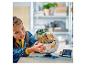 Une fille assemble un set LEGO Star Wars Grogu et sa poussette flottante.