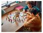 Deux enfants jouent avec un dragon LEGO Ninjago et des figurines sur une table en bois.