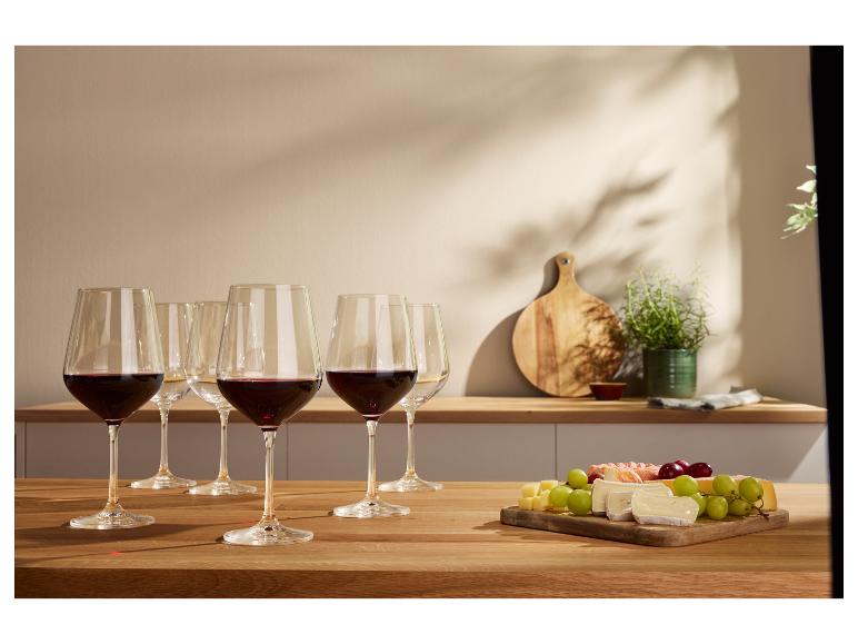 Verres de vin rouge et fromages sur une table en bois.