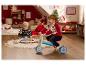 Deux enfants jouent avec des jouets de Noël dans une pièce décorée festivement.