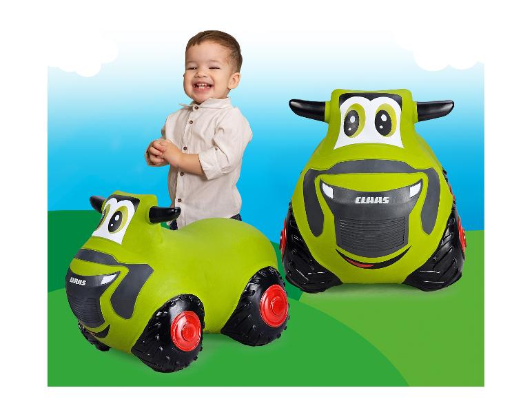 Un enfant joue avec un tracteur Claas en plastique vert.