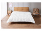 Une couette blanche sur un cadre de lit en bois.