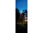 Sapin de Noël extérieur lumineux avec guirlandes en forme d'étoiles sur une pelouse devant une maison.