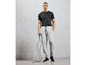 Homme en t-shirt noir et pantalon de survêtement gris tenant une corde à sauter.