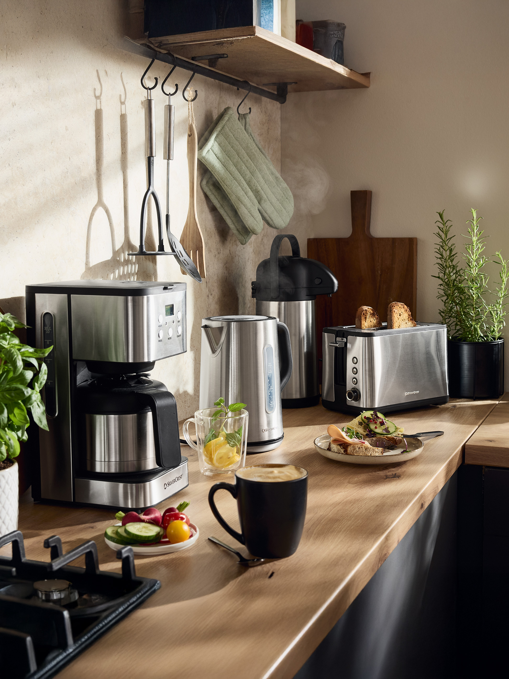 Cafetière SilverCrest, bouilloire et grille-pain dans une cuisine avec nourriture et boissons.