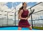 Femme en robe de padel bordeaux avec raquette sur un court de padel avec montagnes en arrière-plan.
