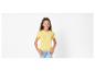 Une jeune femme porte un t-shirt jaune et un jean.