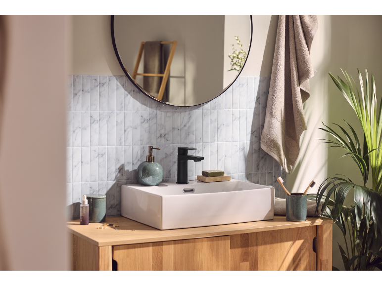 Lavabo de salle de bain avec robinet noir, distributeur de savon et brosses à dents en bambou.