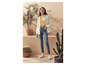 Une femme porte un jean, une chemise blanche et des baskets blanches.