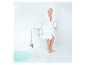 Une femme âgée en peignoir blanc utilise des aides pour la salle de bain.