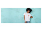 Une femme porte un t-shirt blanc avec un imprimé de palmiers et un jean bleu.