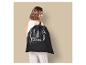 Femme souriante portant un sac de sport noir sur l'épaule.