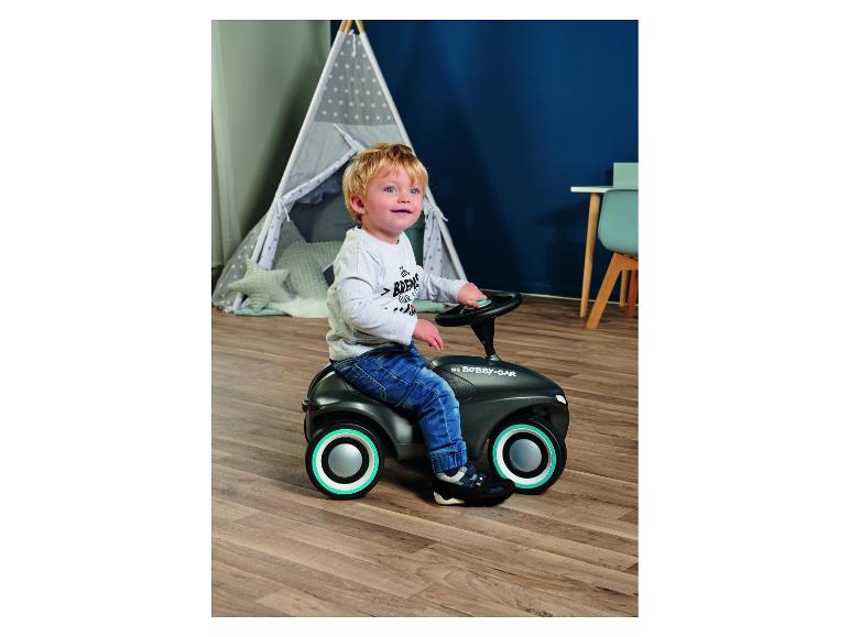 Enfant en bas âge conduisant une voiture à pousser dans une chambre avec une tente de jeu.
