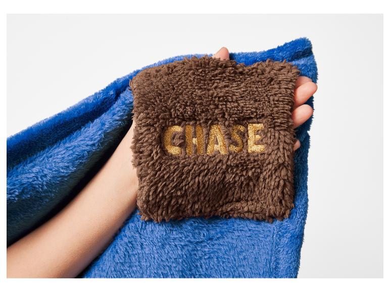 Couverture bleue et marron avec texte brodé 'CHASE' tenue dans une main