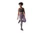 Femme en brassière noire et leggings imprimé léopard violet, debout sur une jambe.