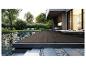Terrasse moderne avec des lames composites foncées, une piscine et des transats dans un jardin.