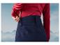 Une femme portant un pantalon bleu foncé avec un pull rouge.