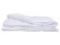 Couette blanche matelassée pliée sur fond blanc.