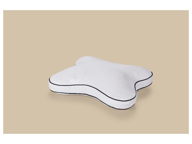 Oreiller ergonomique blanc avec bordure noire sur fond beige