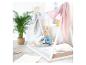Un enfant lit un livre dans un lit tipi blanc avec des couvertures roses et grises.
