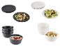 Assiettes et bols en céramique noirs et blancs avec salades et flocons d'avoine aux baies.