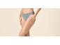 Femme en culotte de coton gris-bleu, les mains sur les cuisses.
