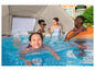 Une fille nage dans une piscine avec une piscine gonflable et un parasol.