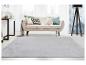 Salon lumineux avec canapé beige, coussins décoratifs et tapis gris clair.