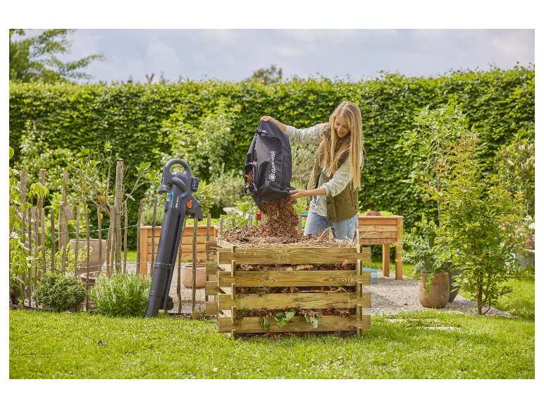 Une femme remplit un composteur avec des feuilles à l'aide d'un souffleur-aspirateur Gardena.