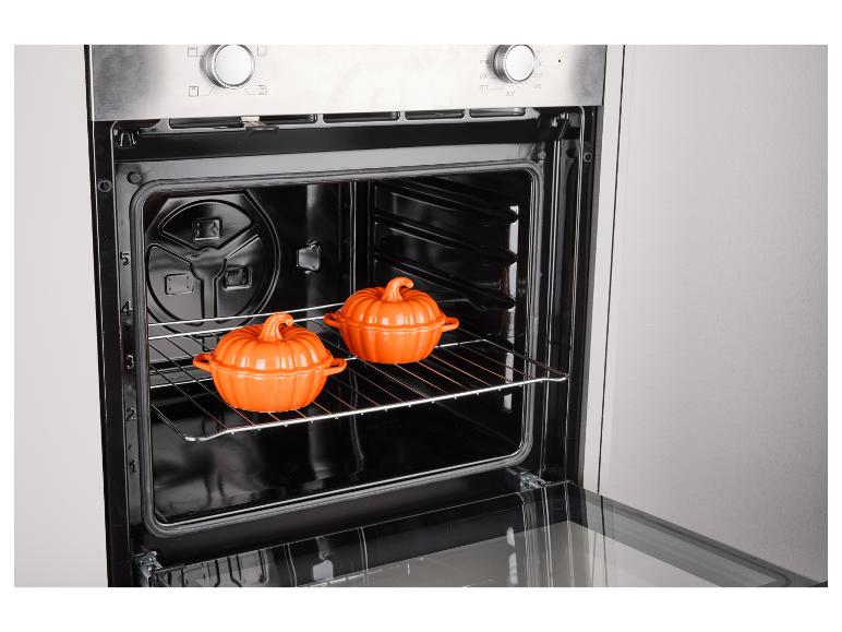 Four avec deux plats orange en forme de citrouille sur une grille.