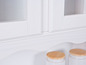 Étagère de cuisine blanche avec des portes en verre et des pots en bois.