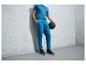 Homme en pantalon de survêtement bleu avec un ballon de fitness.