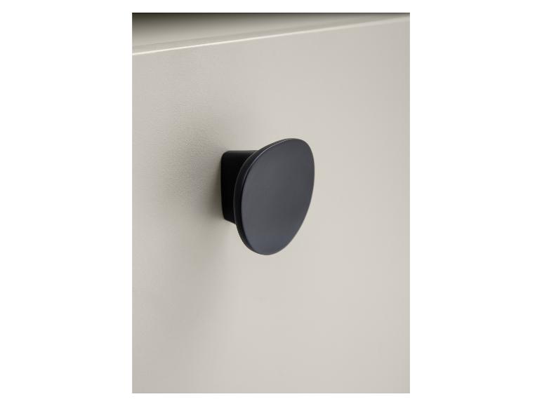 Gros plan d'une poignée ronde noire mate sur une porte d'armoire gris clair.