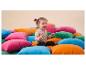 Enfant souriant assis sur une pile de coussins colorés.