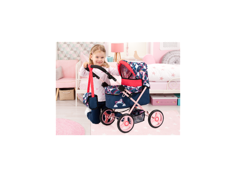 Fille avec poussette de poupée BAYER DESIGN Trendy Unicorn Cosatto dans une chambre d'enfant.