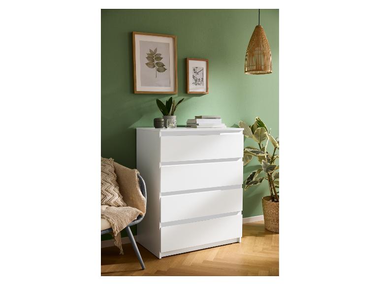 Commode blanche à quatre tiroirs dans une pièce avec un mur vert et un parquet.
