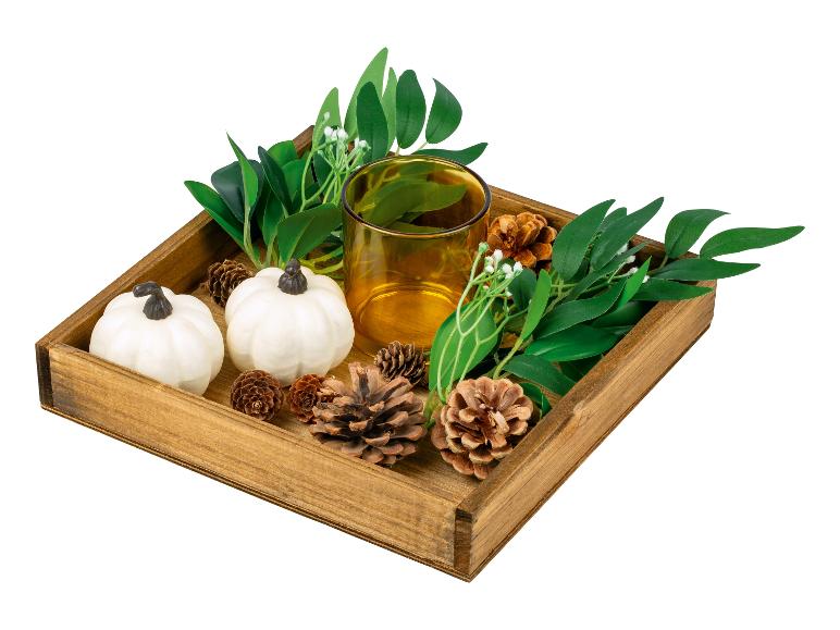 Plateau en bois avec des citrouilles blanches, des pommes de pin et un récipient en verre.