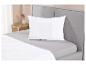 Oreiller blanc sur un lit gris avec une couette.