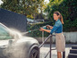 Une femme lave une voiture avec un nettoyeur haute pression Gardena.