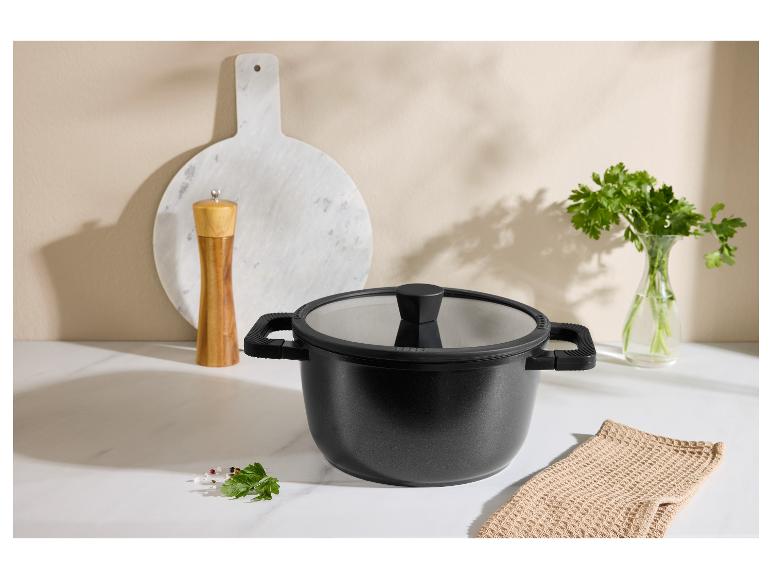 Marmite noire avec couvercle, moulin à poivre, planche à découper et persil dans la cuisine.