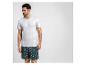 Homme en t-shirt blanc et short de bain imprimé palmiers.