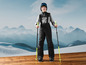 Un garçon en tenue de ski avec des bâtons de ski, prêt à skier.