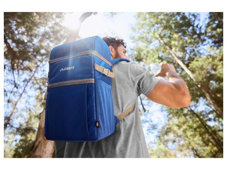 Homme avec sac à dos isotherme bleu buvant de l'eau en forêt.